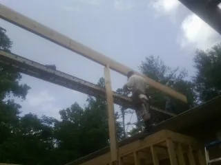 Carpenter setting a ridge beam over a new addition frame — Ice Dam Removal by Roofing Brothers in Lynbrook