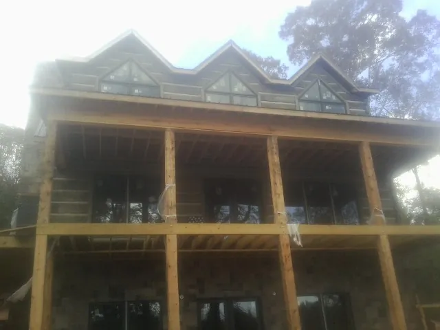 Dormers and porch framing on a large log home under construction — Roof Coating work by our crew in Lynbrook