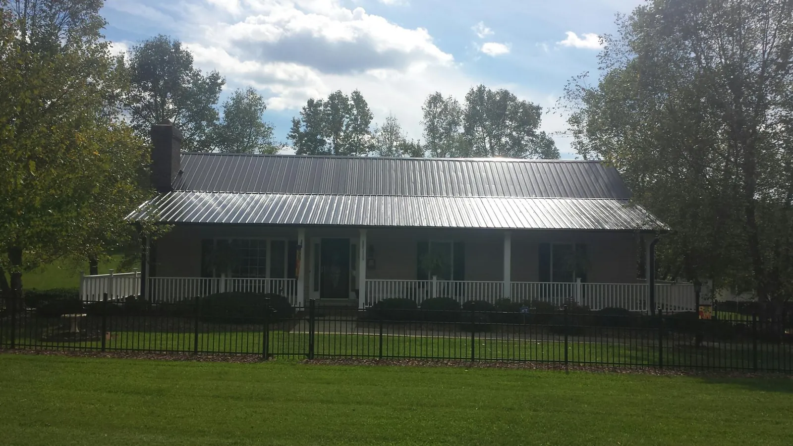 Gray metal roof on a brick ranch with a full width front porch — Gutter Guard Installation work by our crew in Lynbrook