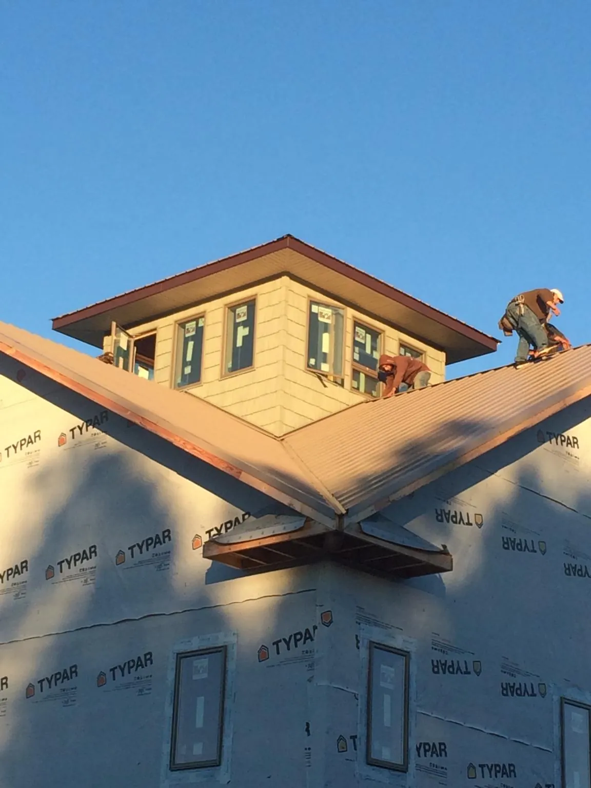 Roofers working around a rooftop cupola on a new metal roof at sunset — Roof Waterproofing in Lynbrook by Roofing Brothers